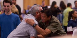 Two men shake hands and embrace in a crowd of people